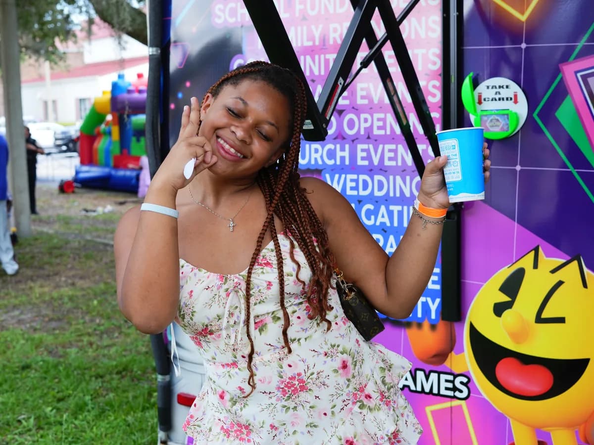 A young woman smiling in front of the games and inflatables at a family fun day