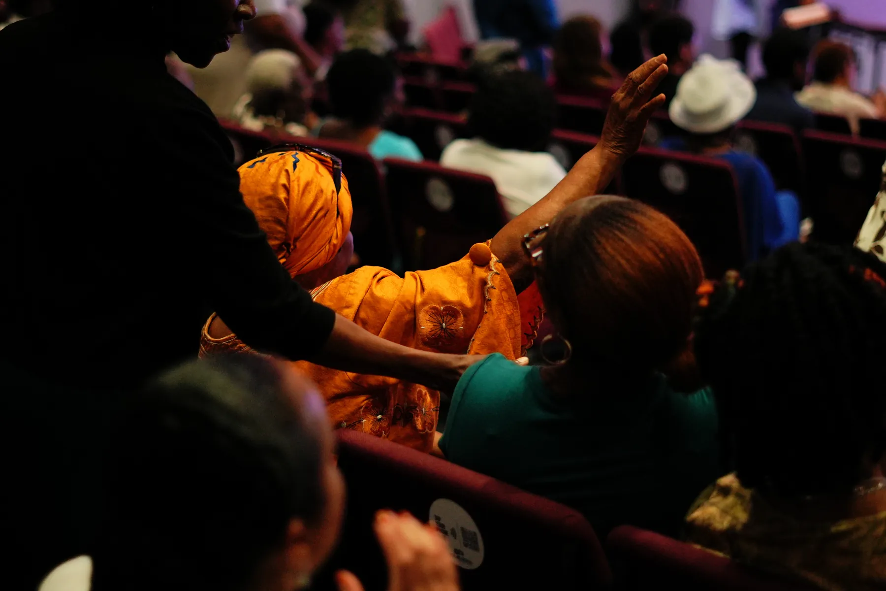 The congregation with hands raised in a darkened sanctuary