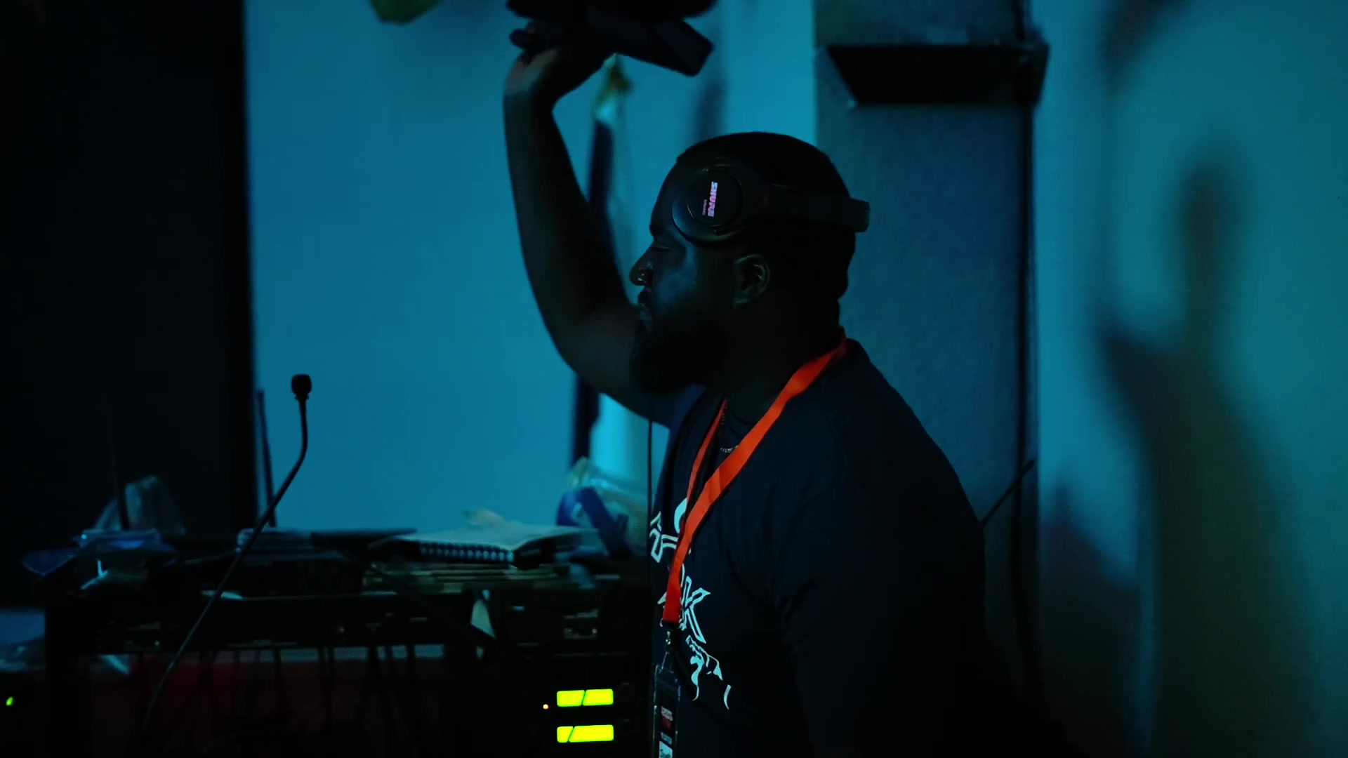 Young people at a Solid Rock youth night, hands raised in a darkened room lit in blue and magenta